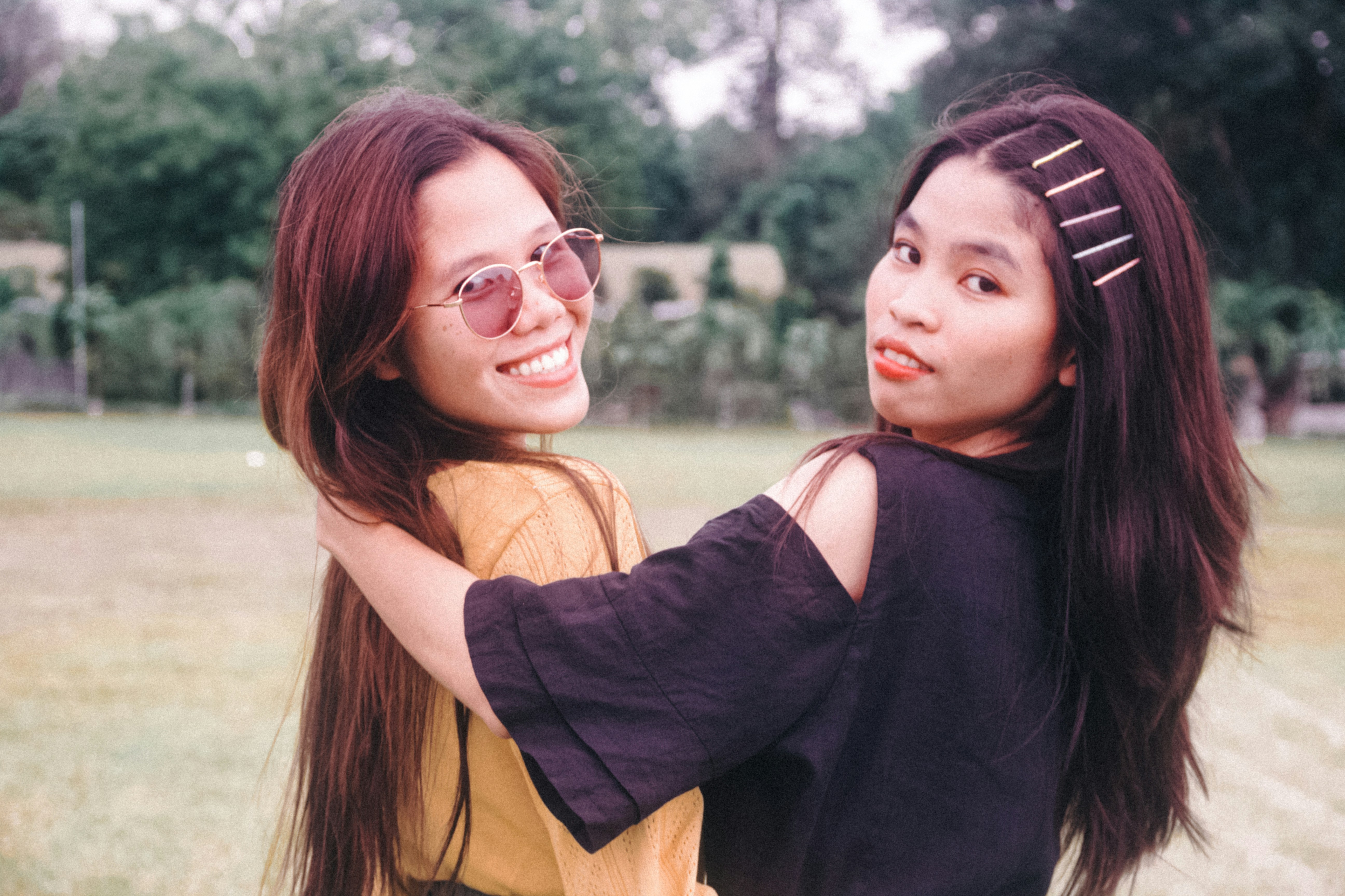 two women standing next to each other in a field