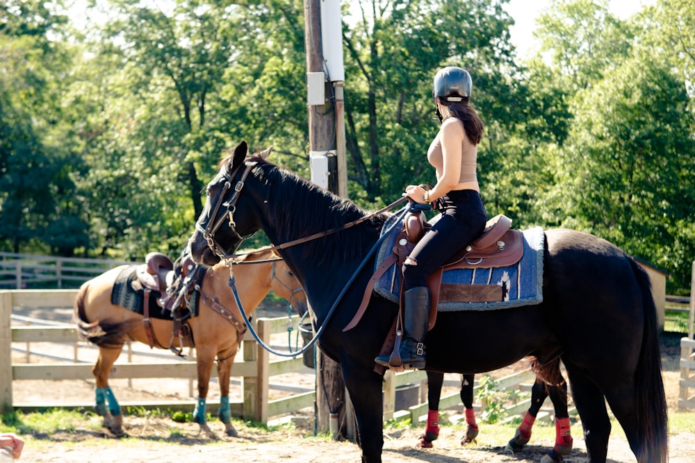 a woman riding on the back of a black horse