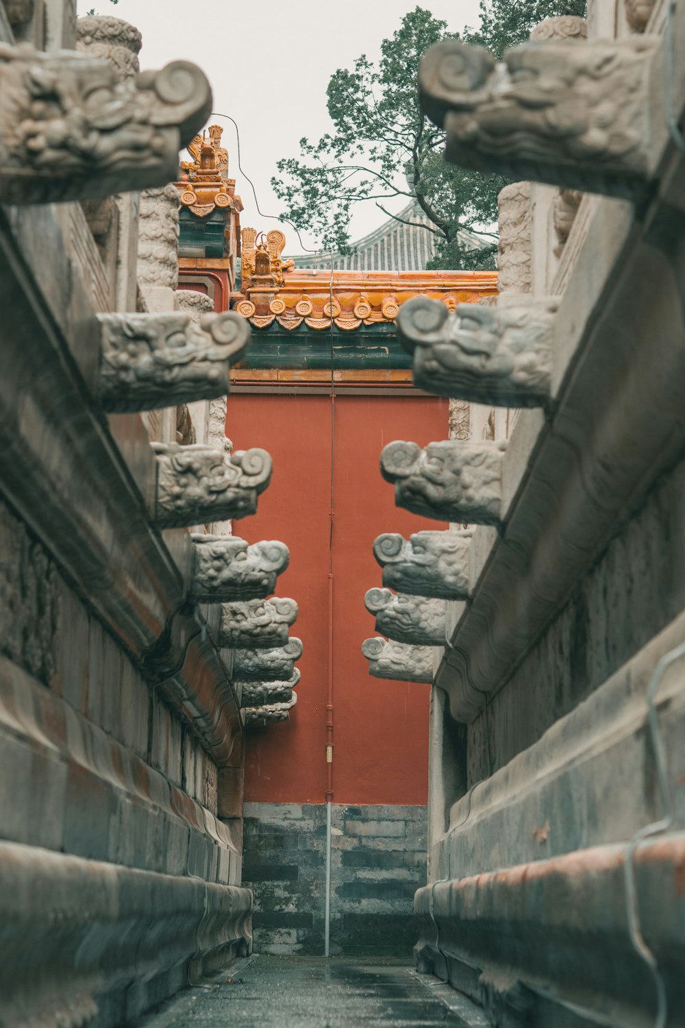 a narrow alley with a red wall and a golden gate