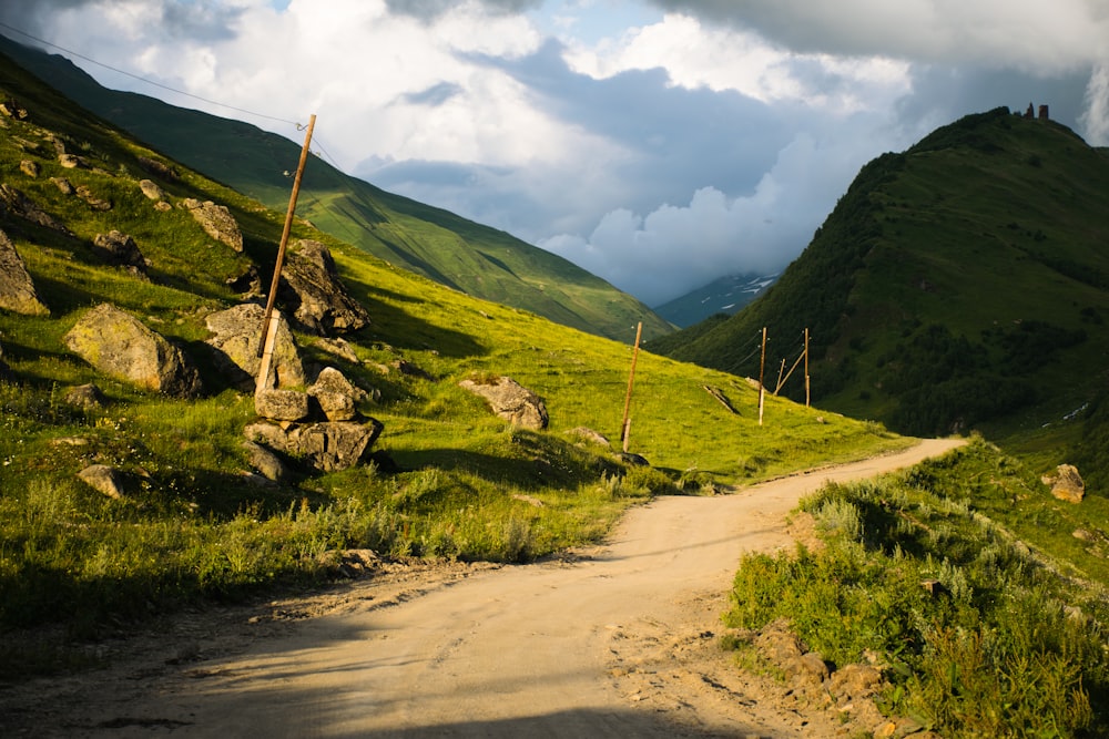 a dirt road going through a lush green valley