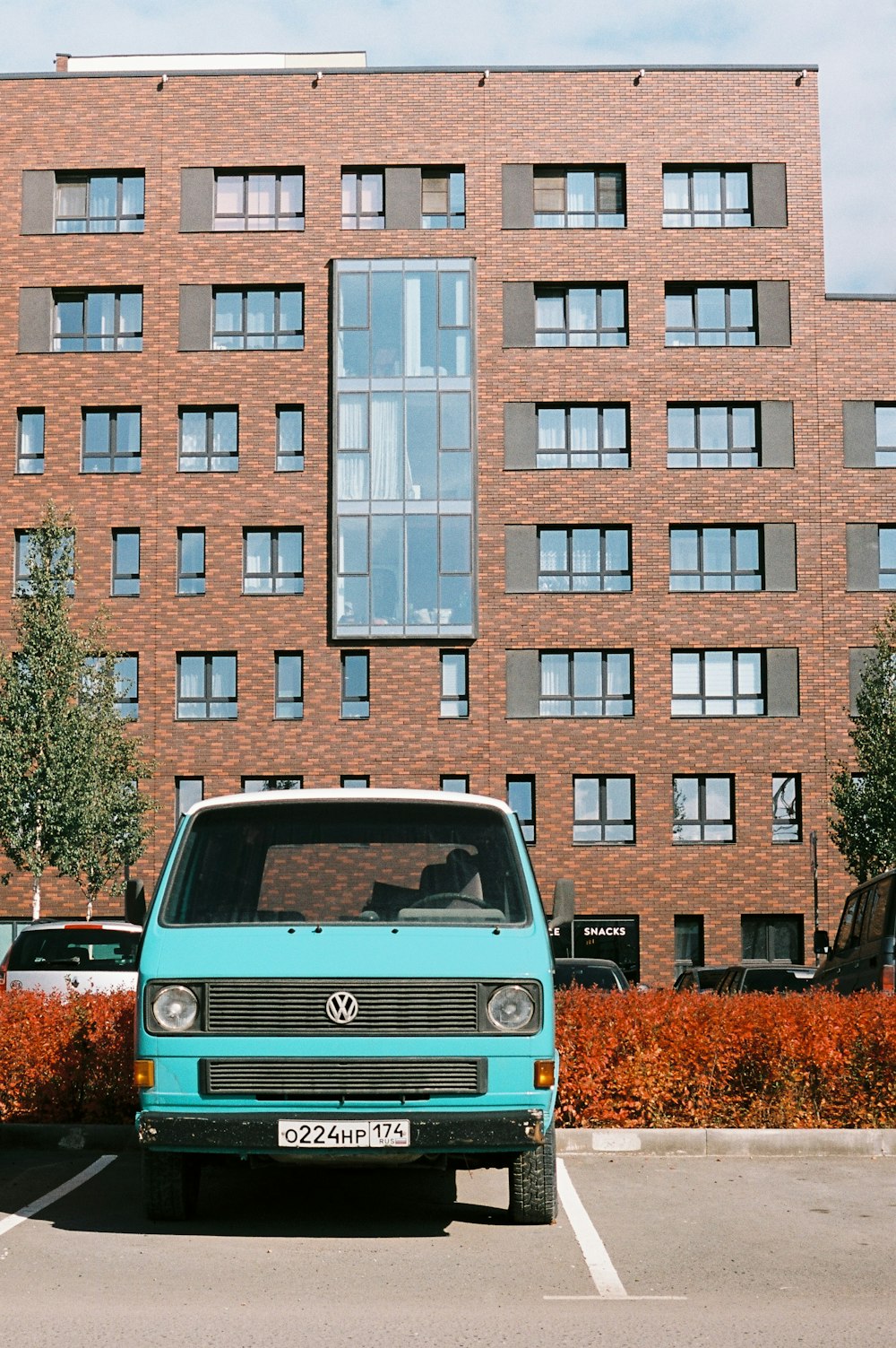 a blue van parked in a parking lot in front of a brick building