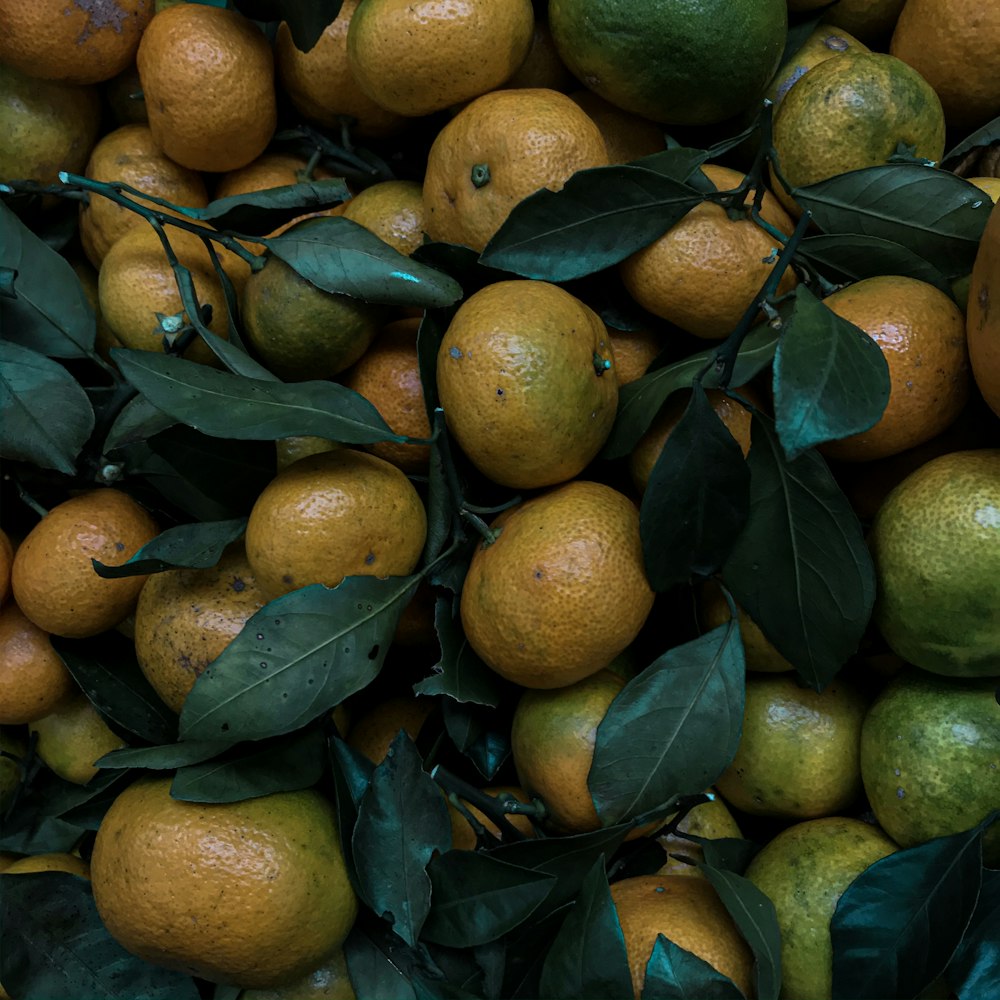 a pile of oranges with leaves on them