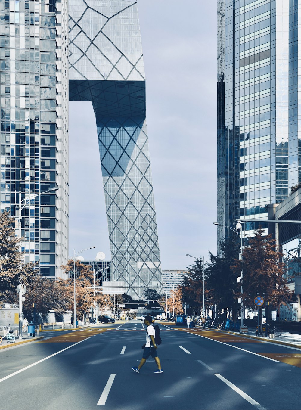 a person walking across a street in front of tall buildings