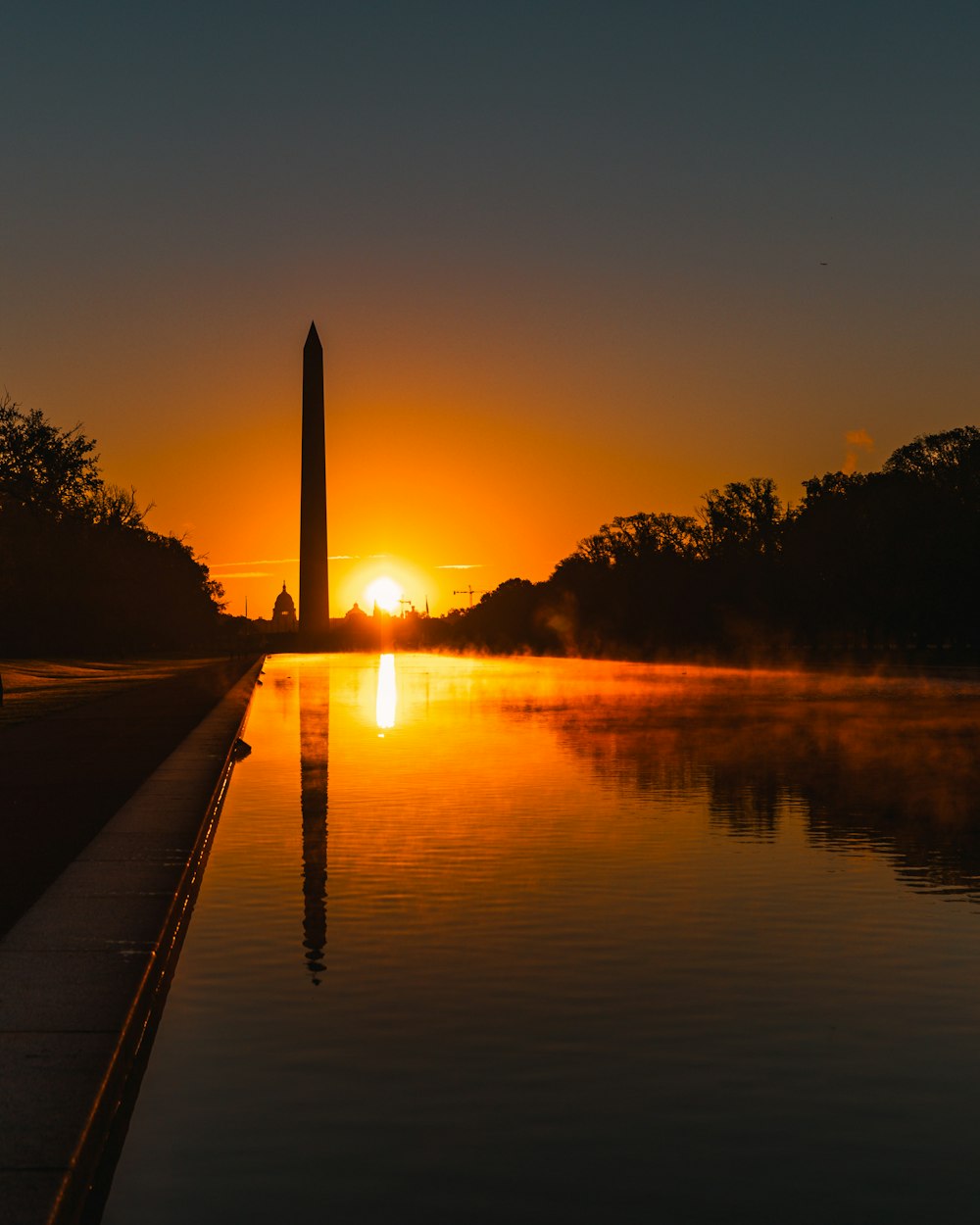 the sun is setting over the washington monument