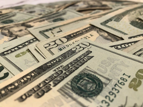 A vibrant close-up of US dollar bills fanned out on a wooden table.