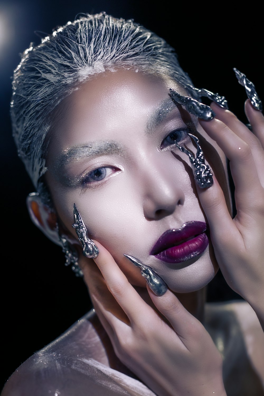 a woman with silver nails and a manicure on her face