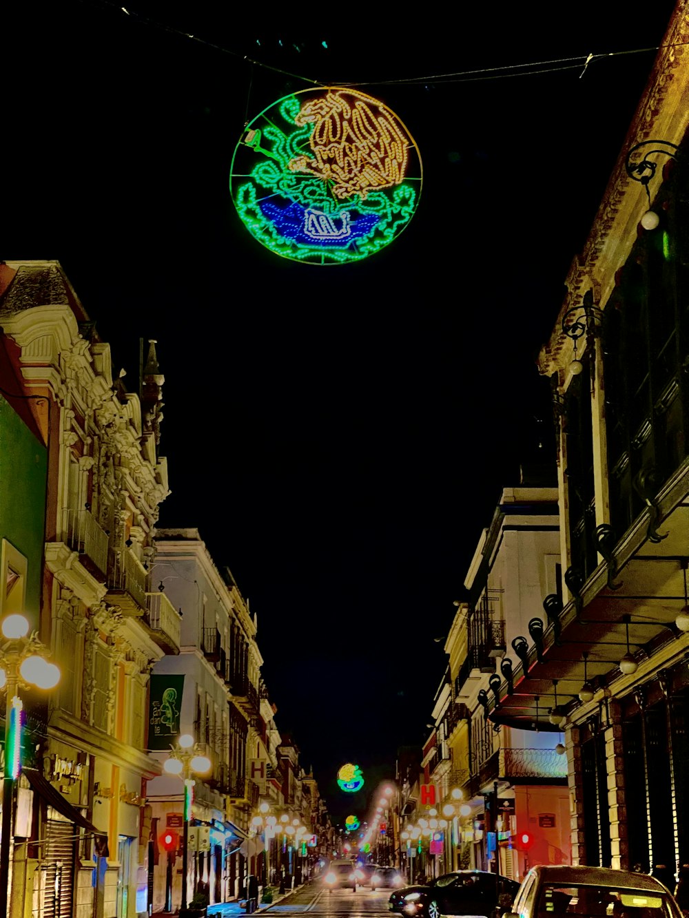 a city street at night with a neon sign above it