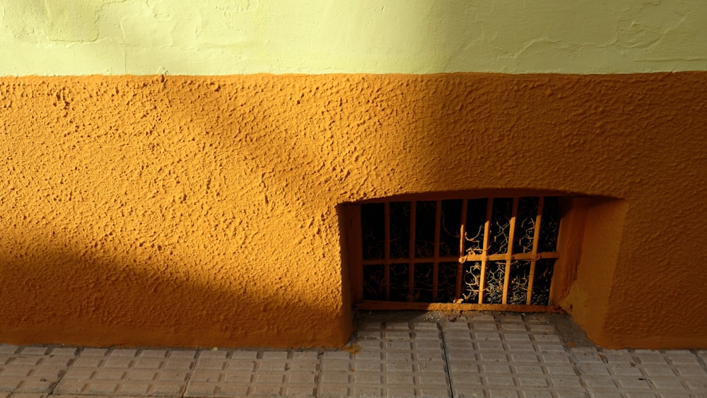 a yellow building with a barred window on the side of it