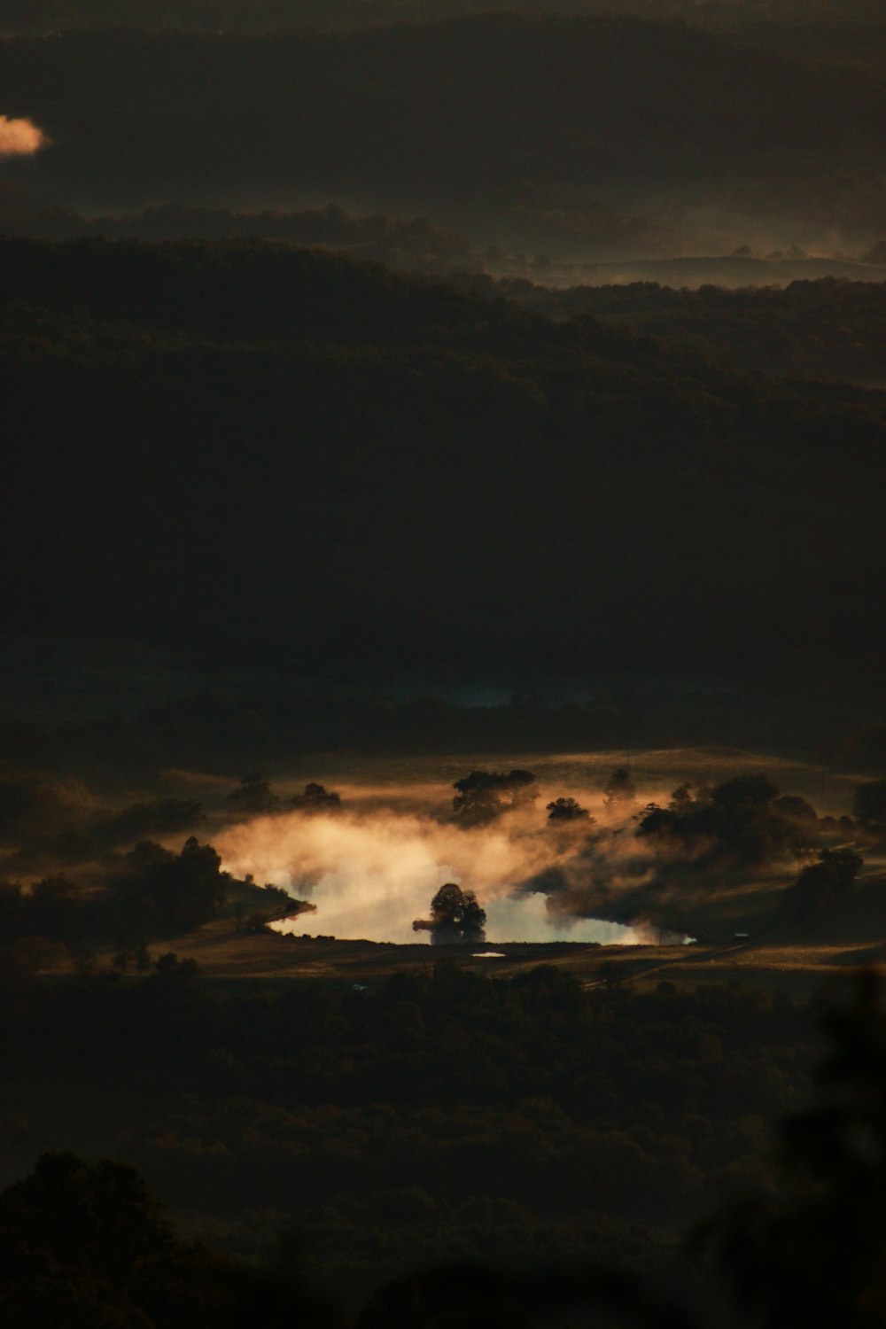 a dark sky with clouds and trees in the foreground