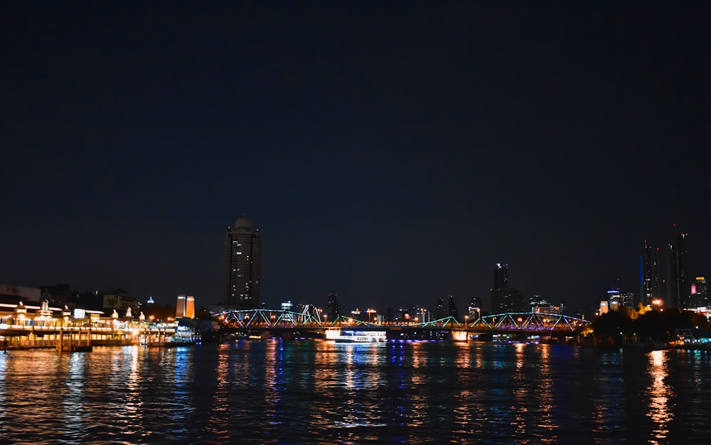 a night view of a river with a bridge and a city in the background