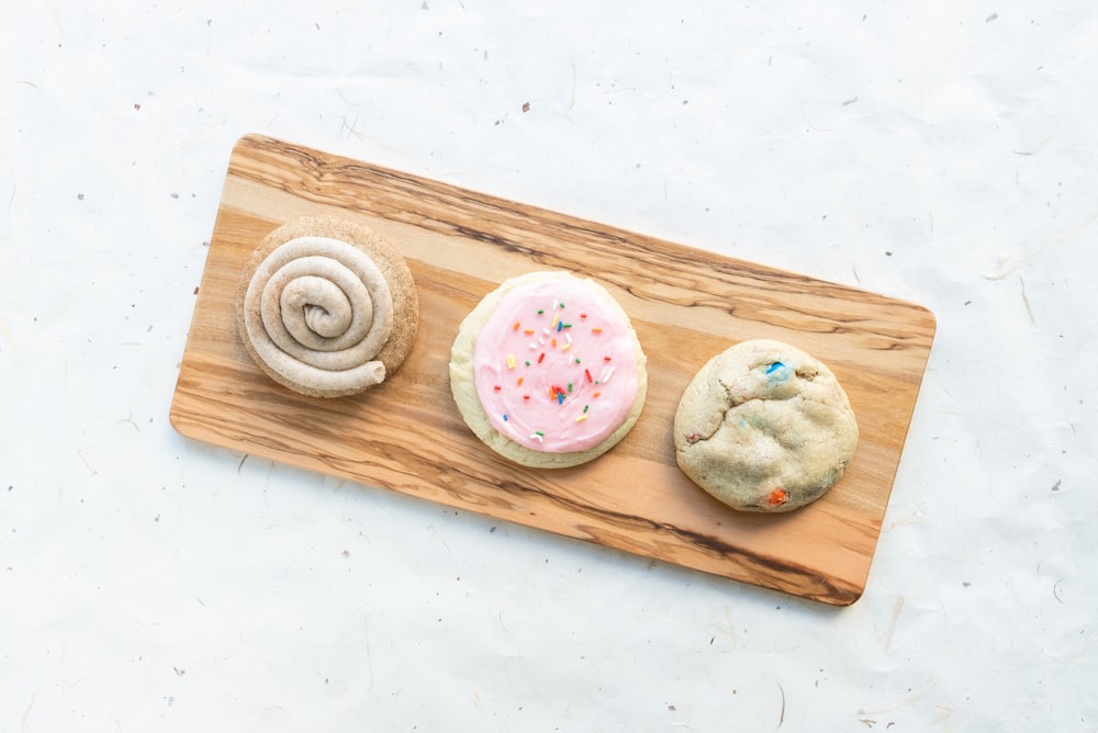 a wooden cutting board topped with three cookies