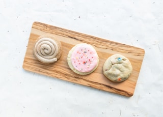 a wooden cutting board topped with three cookies