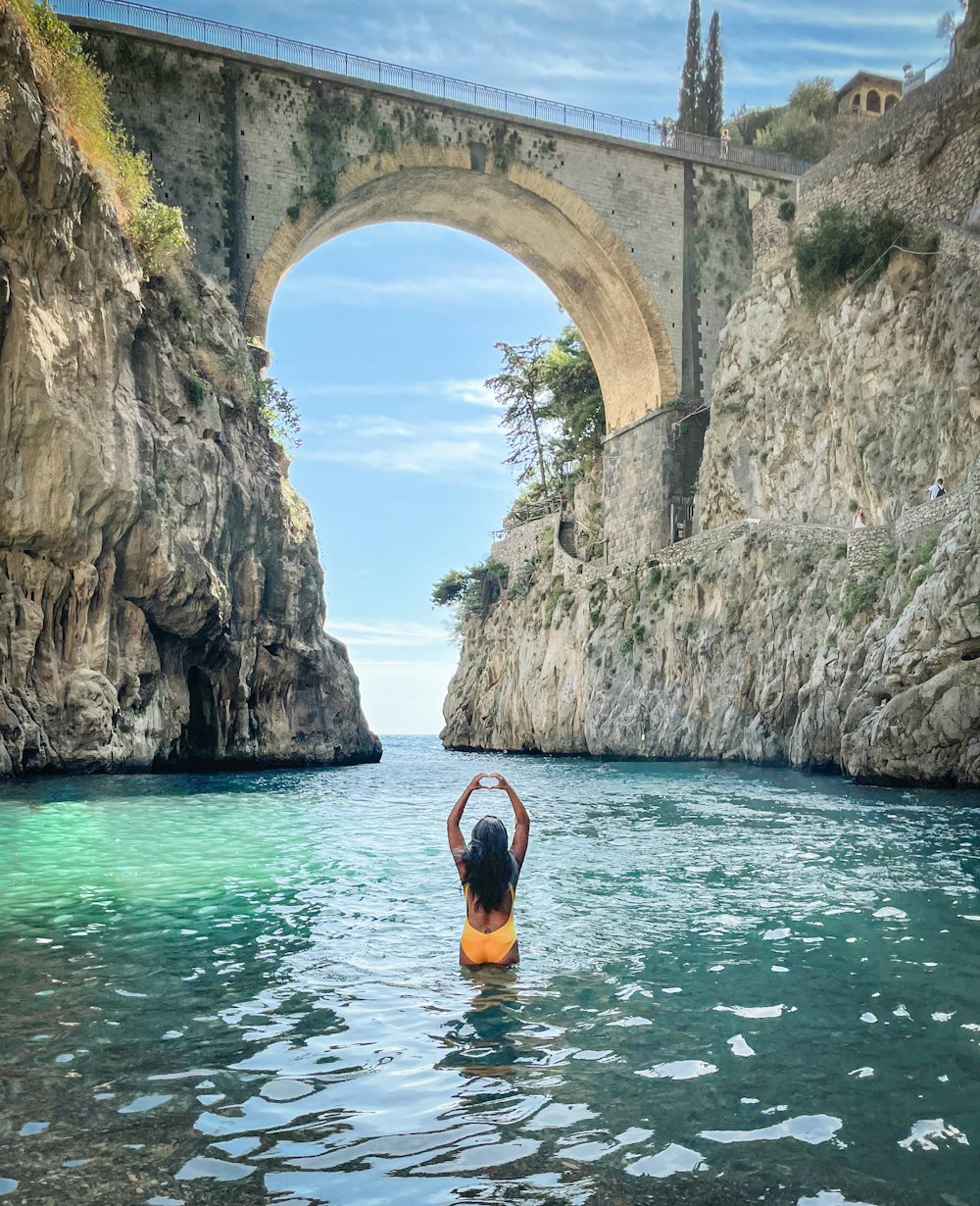 a person in a body of water with a bridge in the background