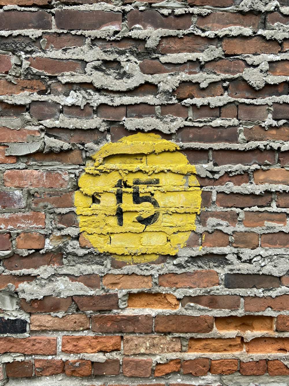 a yellow and black sign on a brick wall