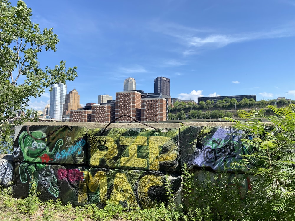 a wall covered in graffiti with a city in the background