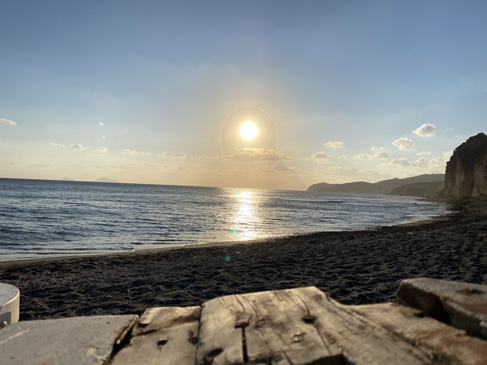 a wooden bench sitting on top of a sandy beach