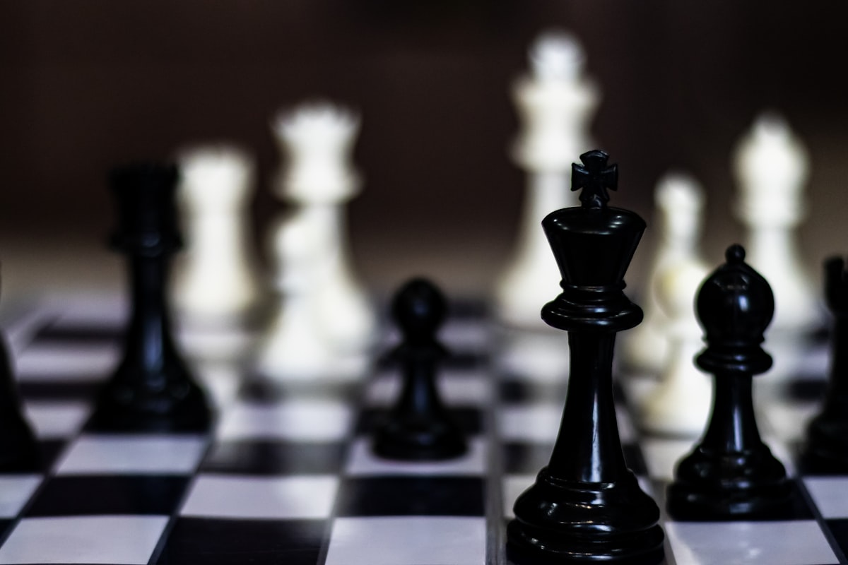 An image of a black and white checkered chess board with smooth polished black and white chess pieces.