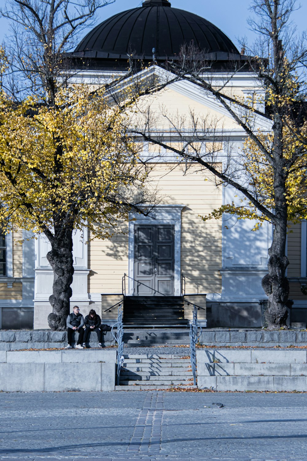 two people sitting on a bench in front of a building