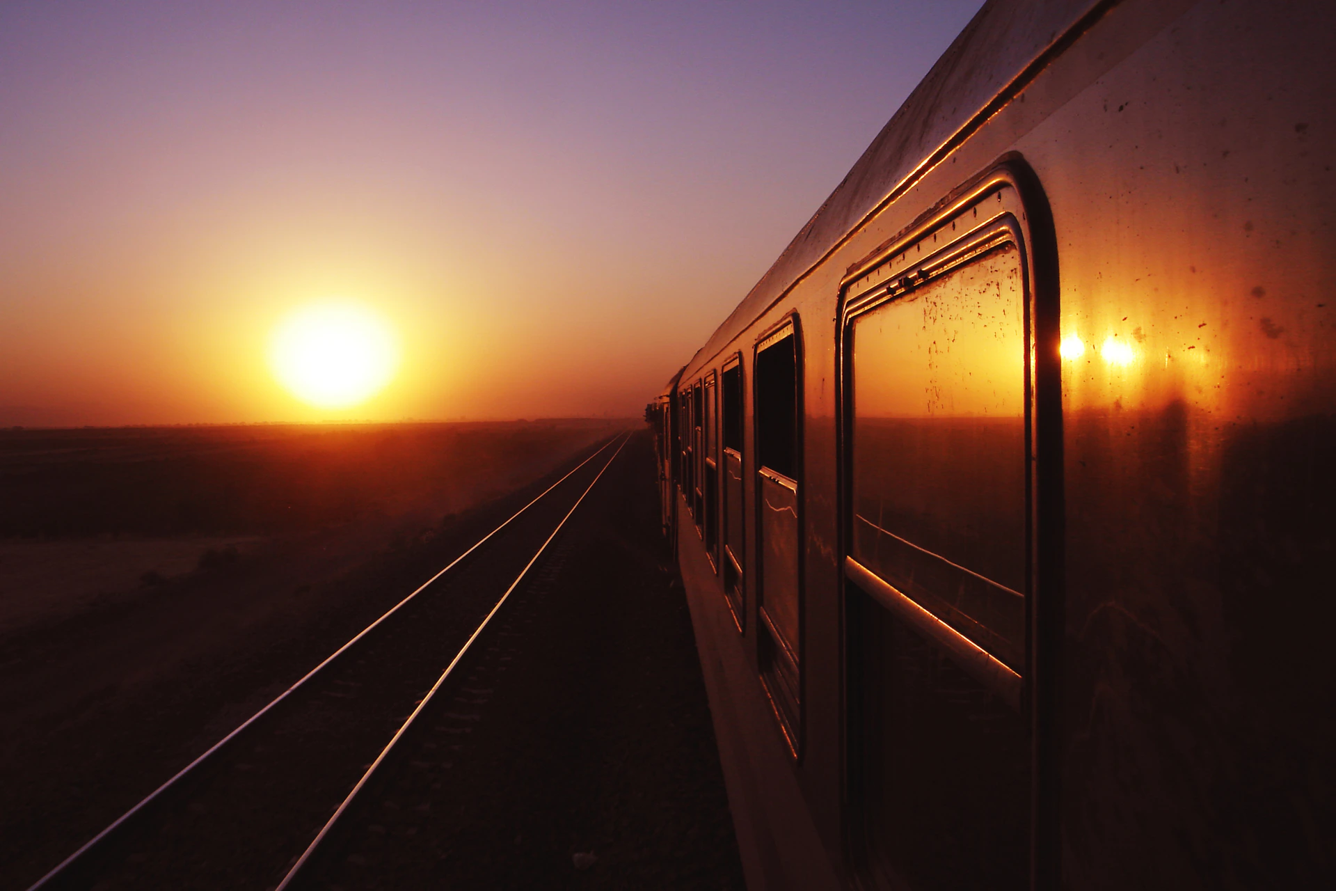 the sun is setting over the horizon of a train