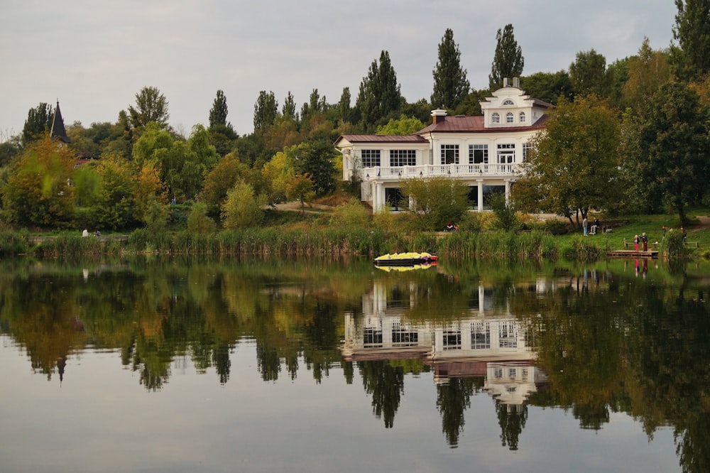 a house sitting on top of a lush green hillside next to a lake