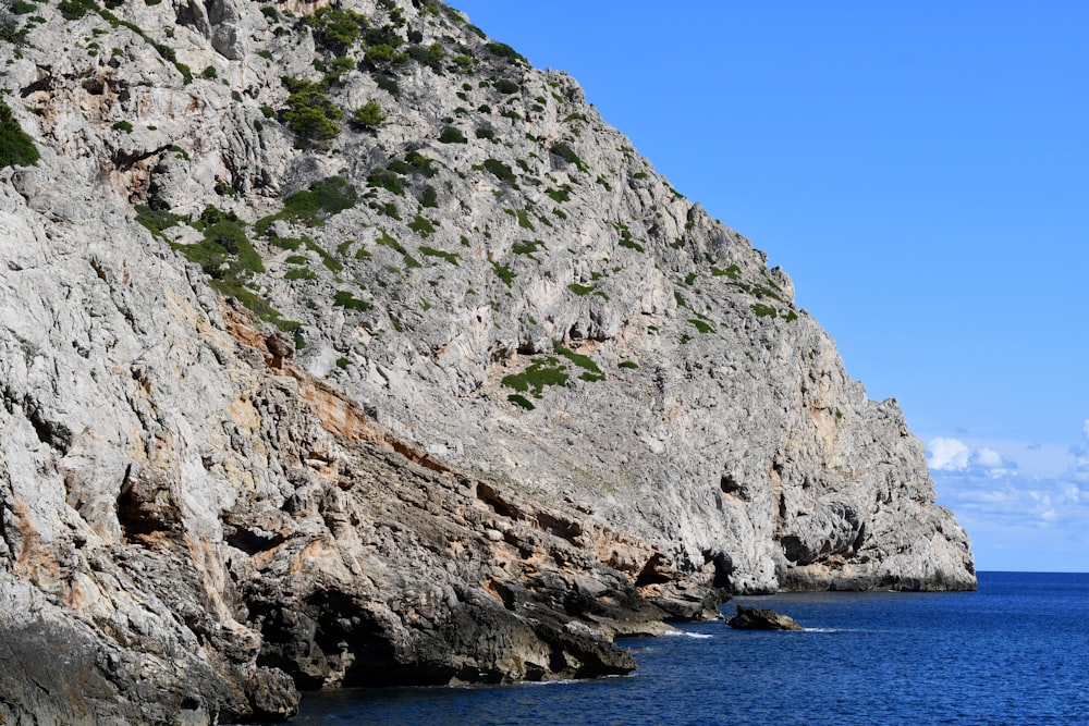 a rocky cliff on the side of a body of water