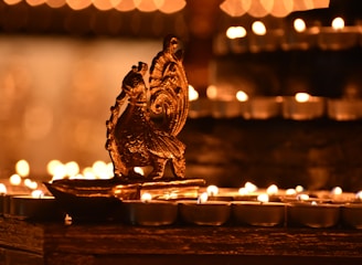 a close up of a lit candle with a statue of an owl