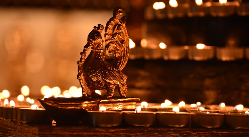 a close up of a lit candle with a statue of an owl