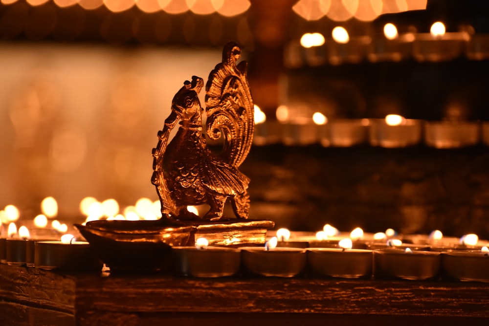 a close up of a lit candle with a statue of an owl