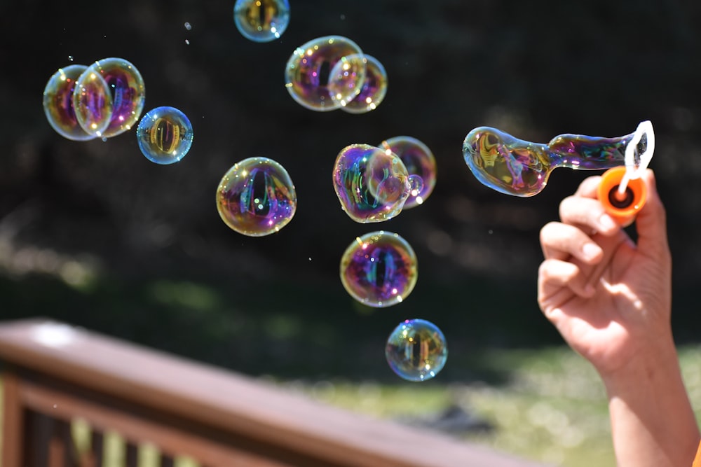 a person holding a pair of scissors in front of soap bubbles