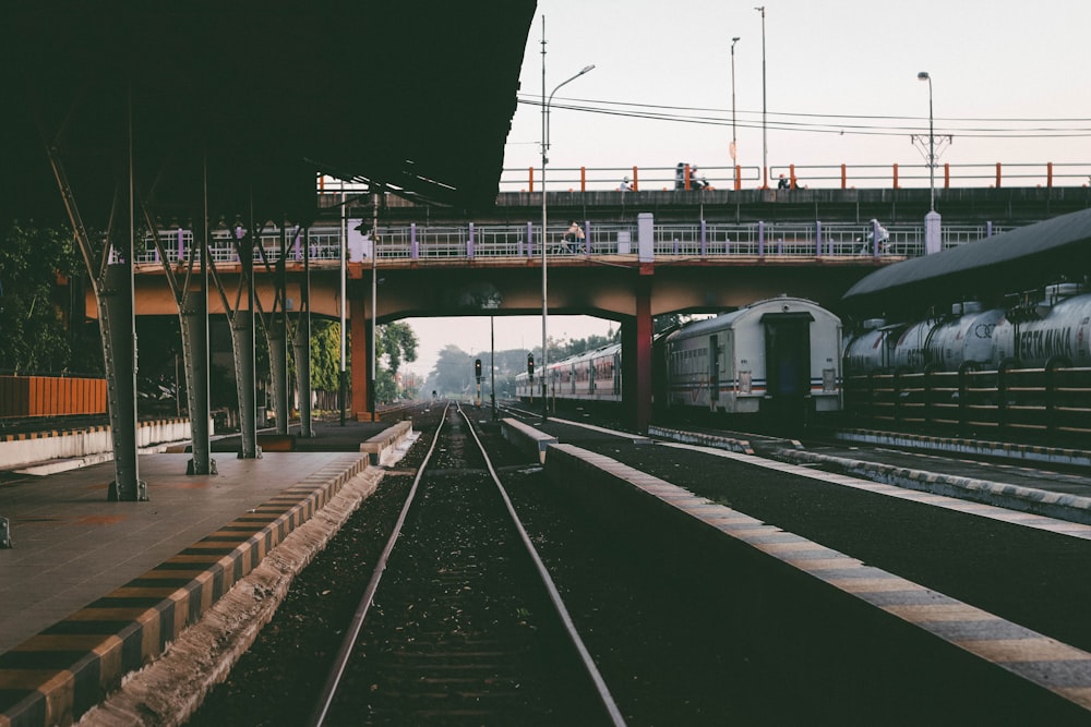 a train traveling under a bridge next to a train station