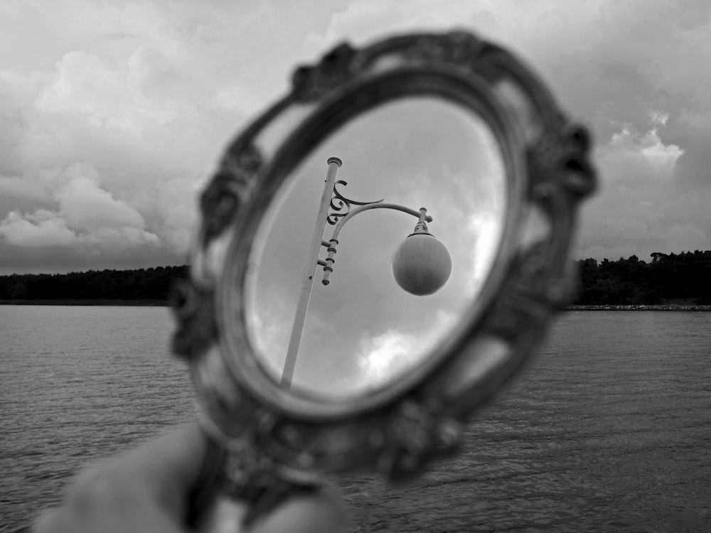 a person holding a mirror with a street light in it