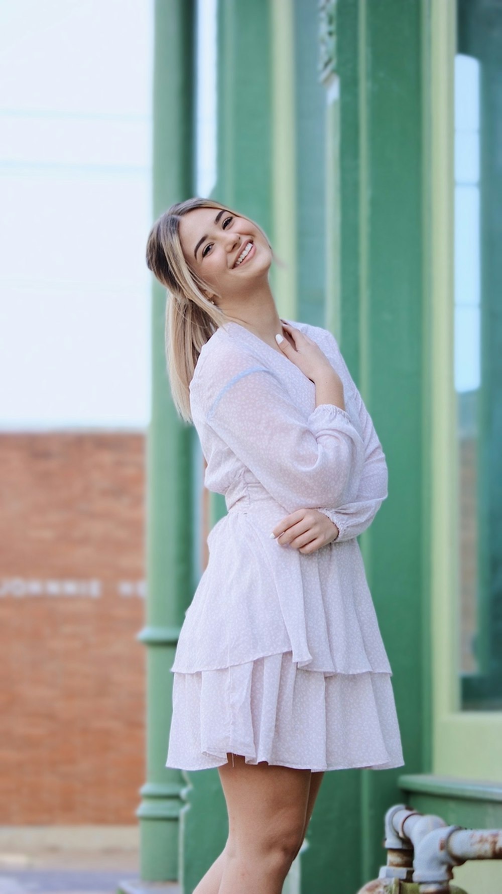 Una donna in un vestito bianco è in posa per una foto