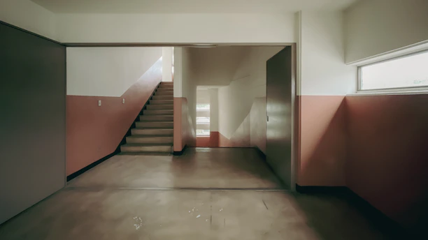 A clean and bright apartment building hallway with polished floors and well-lit stairs.