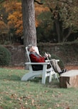 a man sitting on a white bench next to a tree