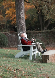 a man sitting on a white bench next to a tree
