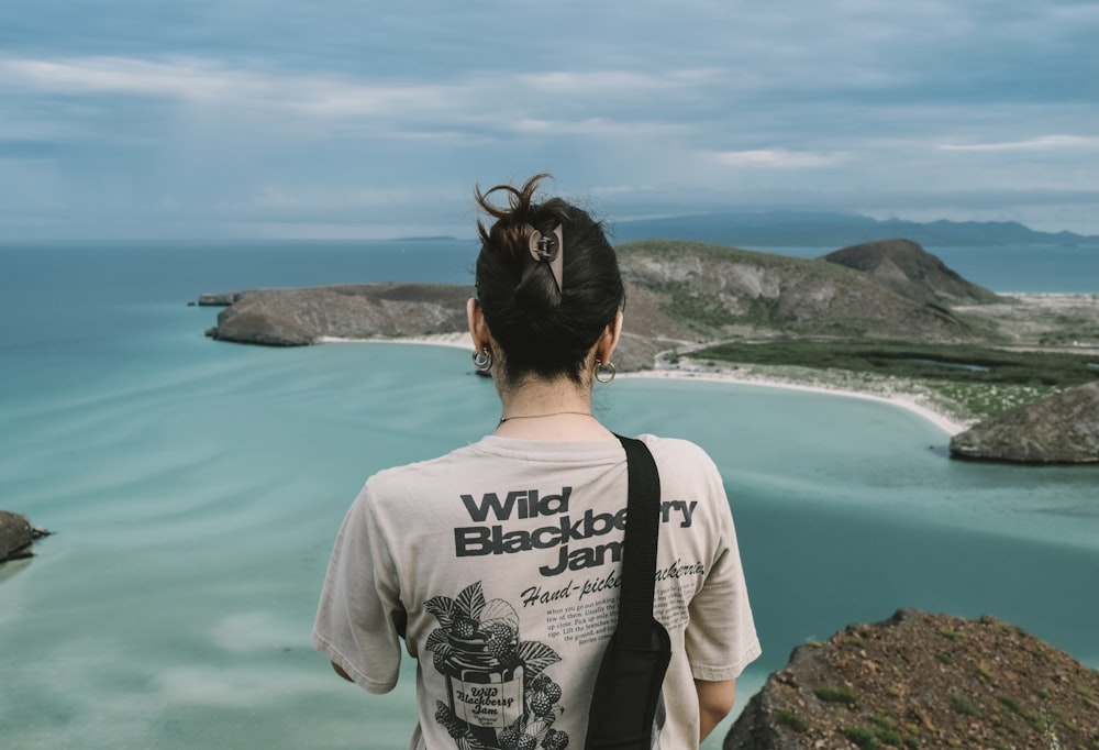 a woman standing on top of a cliff next to the ocean