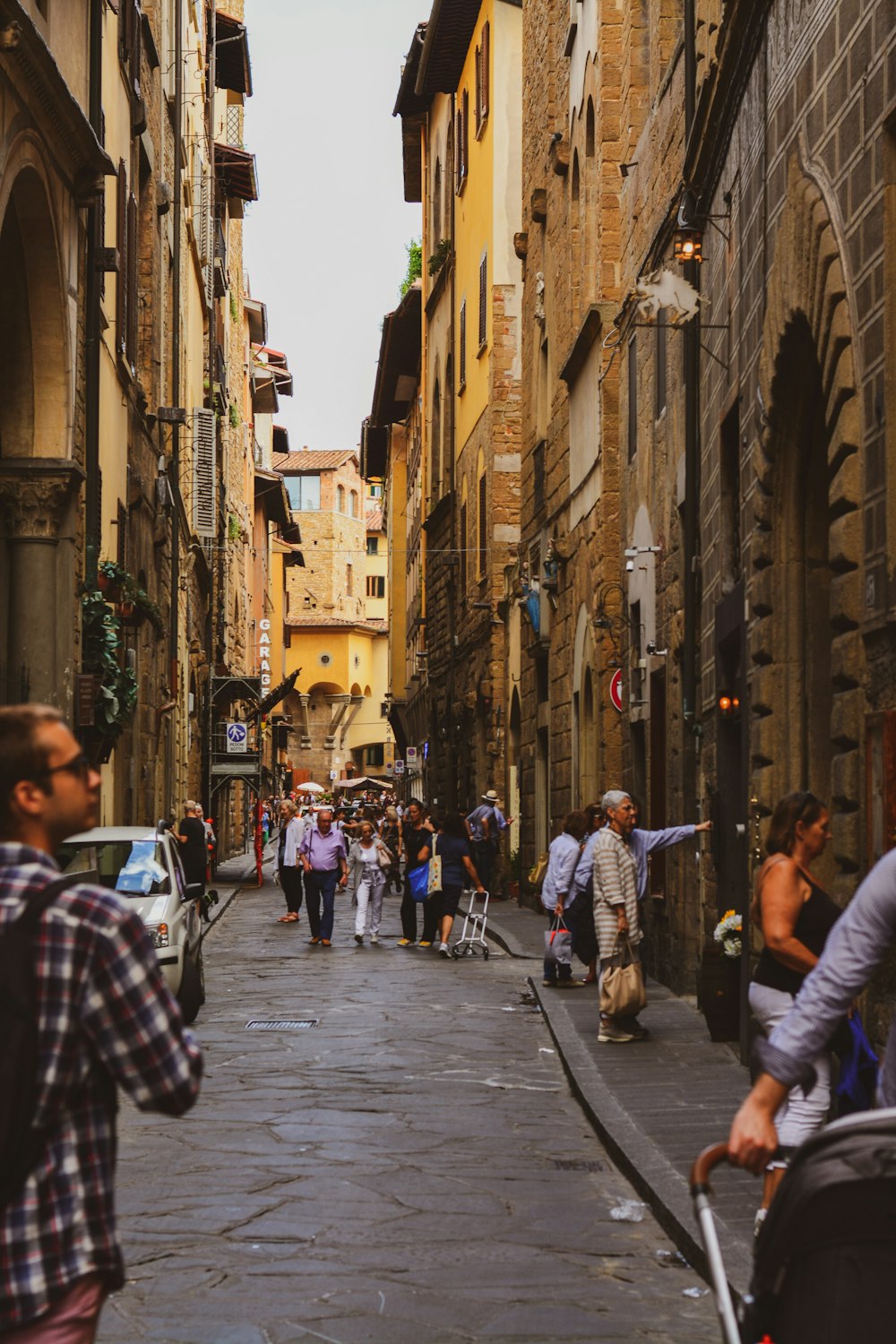 a group of people walking down a street next to tall buildings