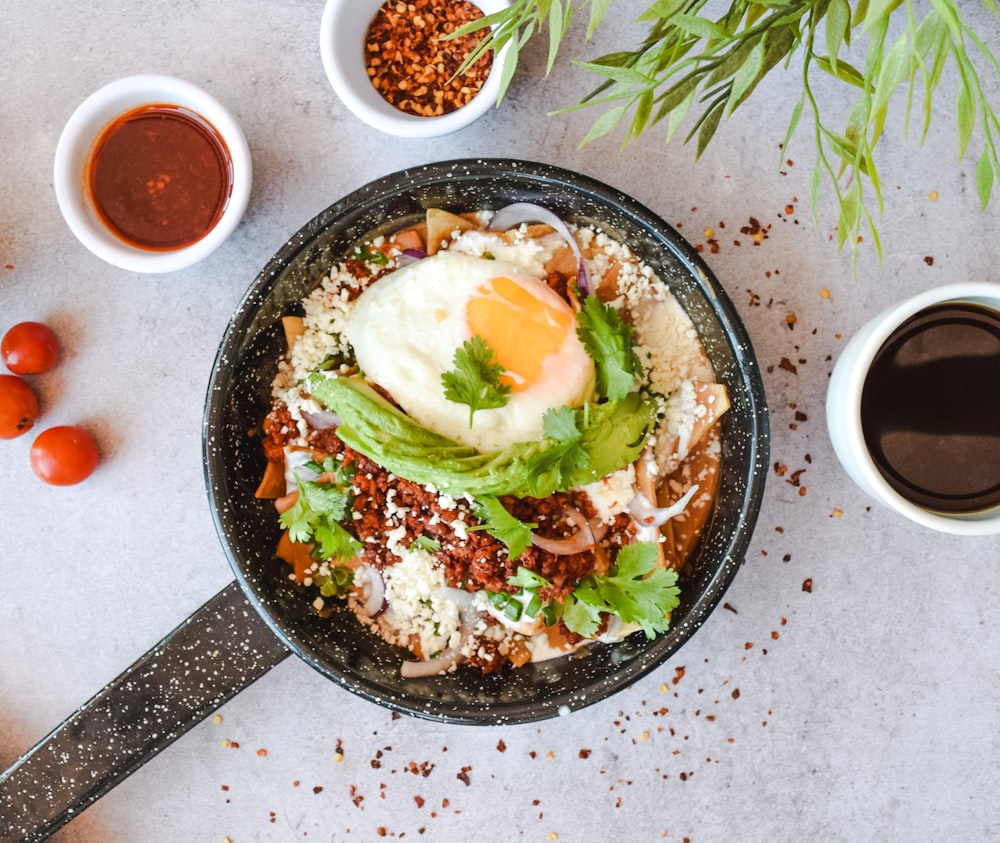 a pan filled with food next to two cups of coffee