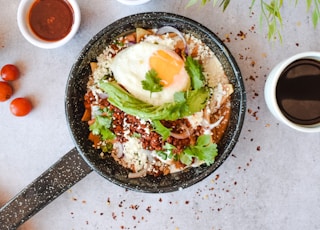 a pan filled with food next to two cups of coffee