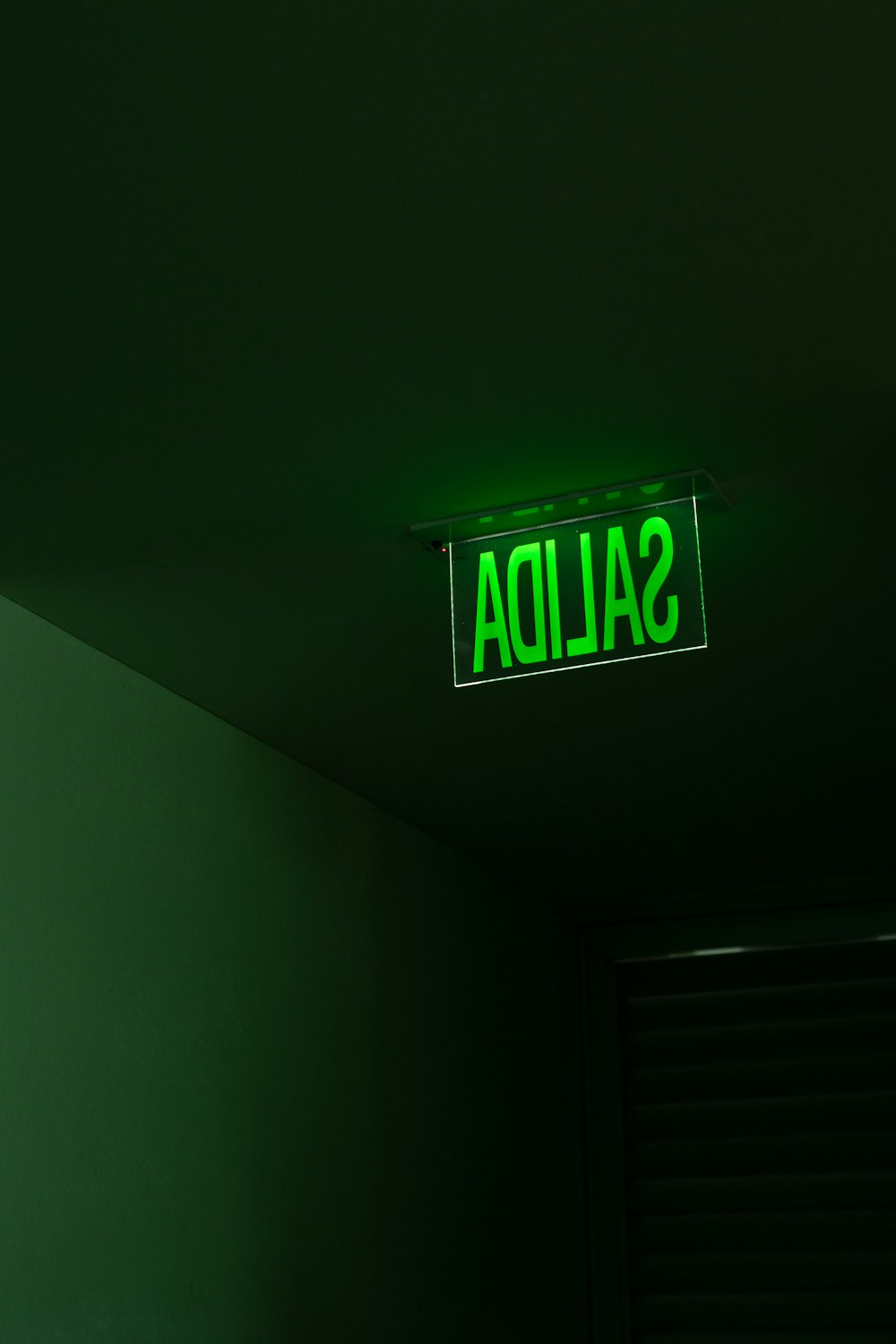 a green sign that reads salida hanging from the ceiling