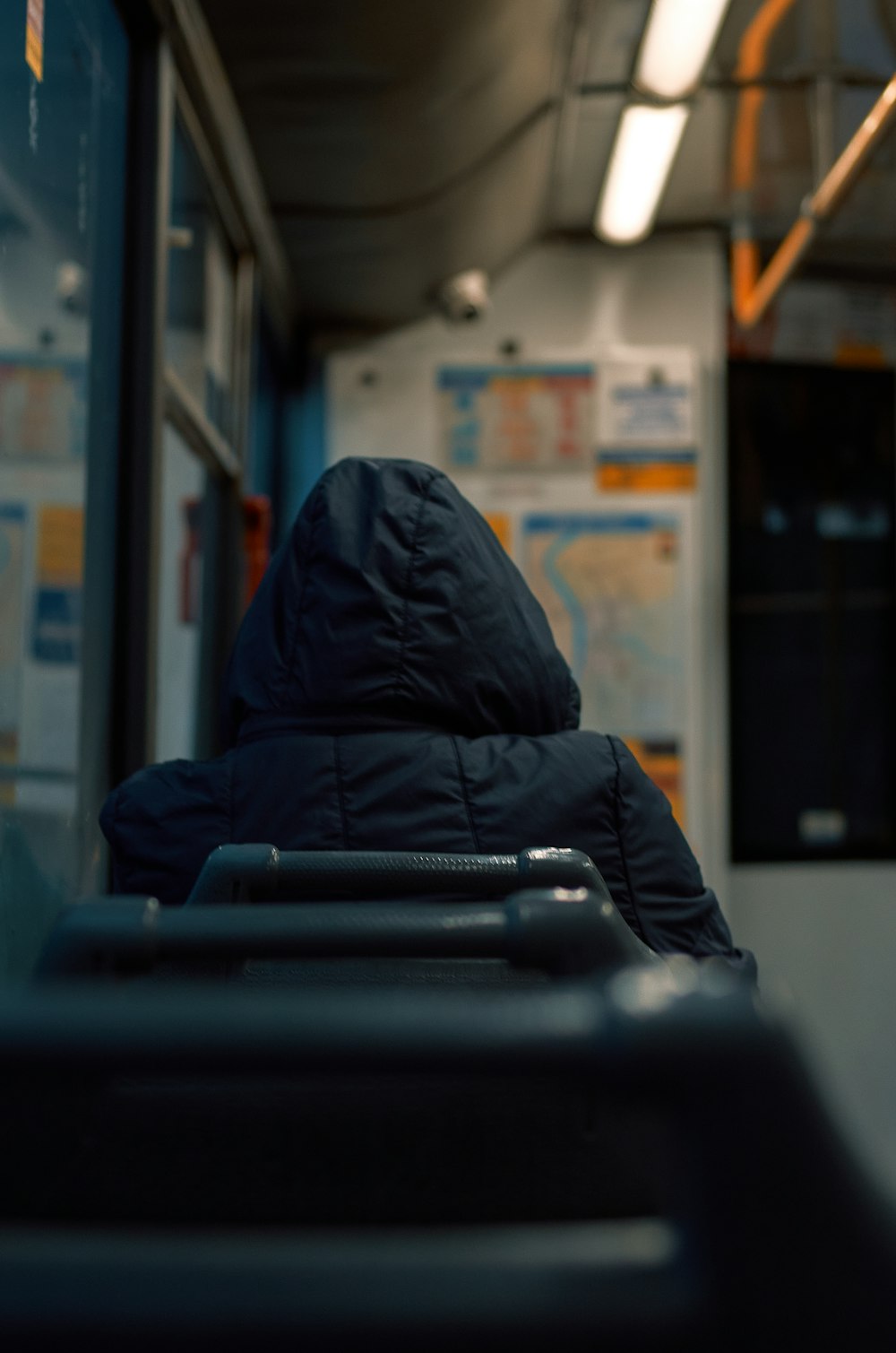a person in a hooded jacket sitting on a bus