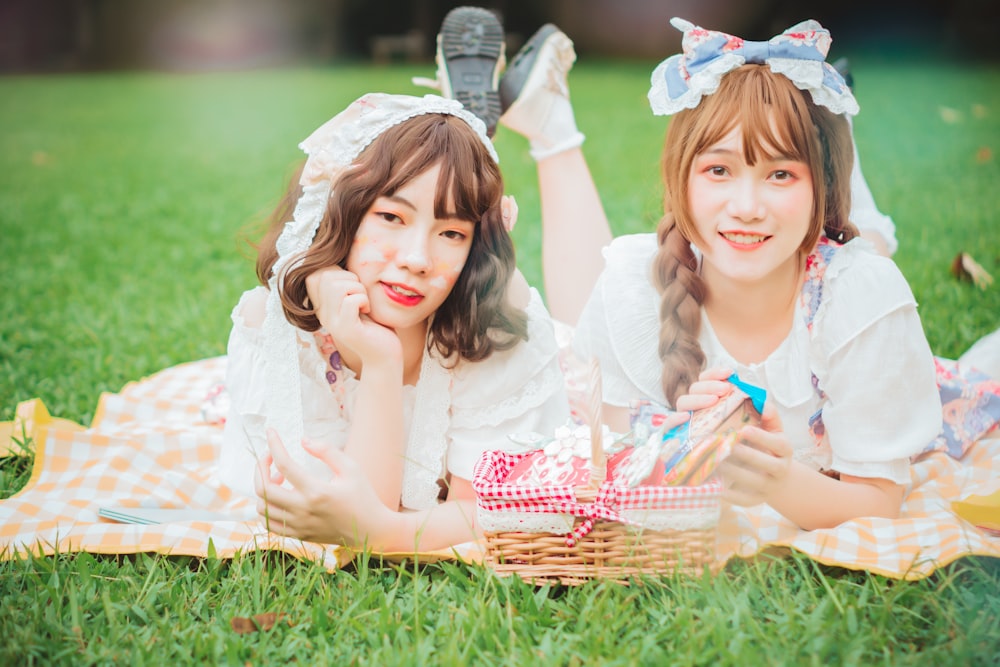 two young girls laying on a blanket in the grass