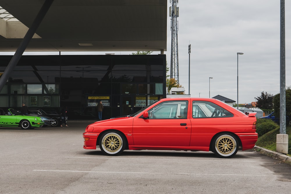 a red car parked in a parking lot next to a green car