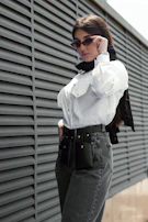 A model wearing a crisp classic shirt with a matching belt, standing by a sunlit window.