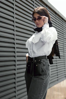A model wearing a crisp classic shirt with a matching belt, standing by a sunlit window.