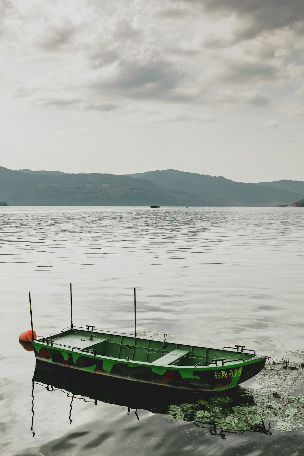 a small green boat floating on top of a lake