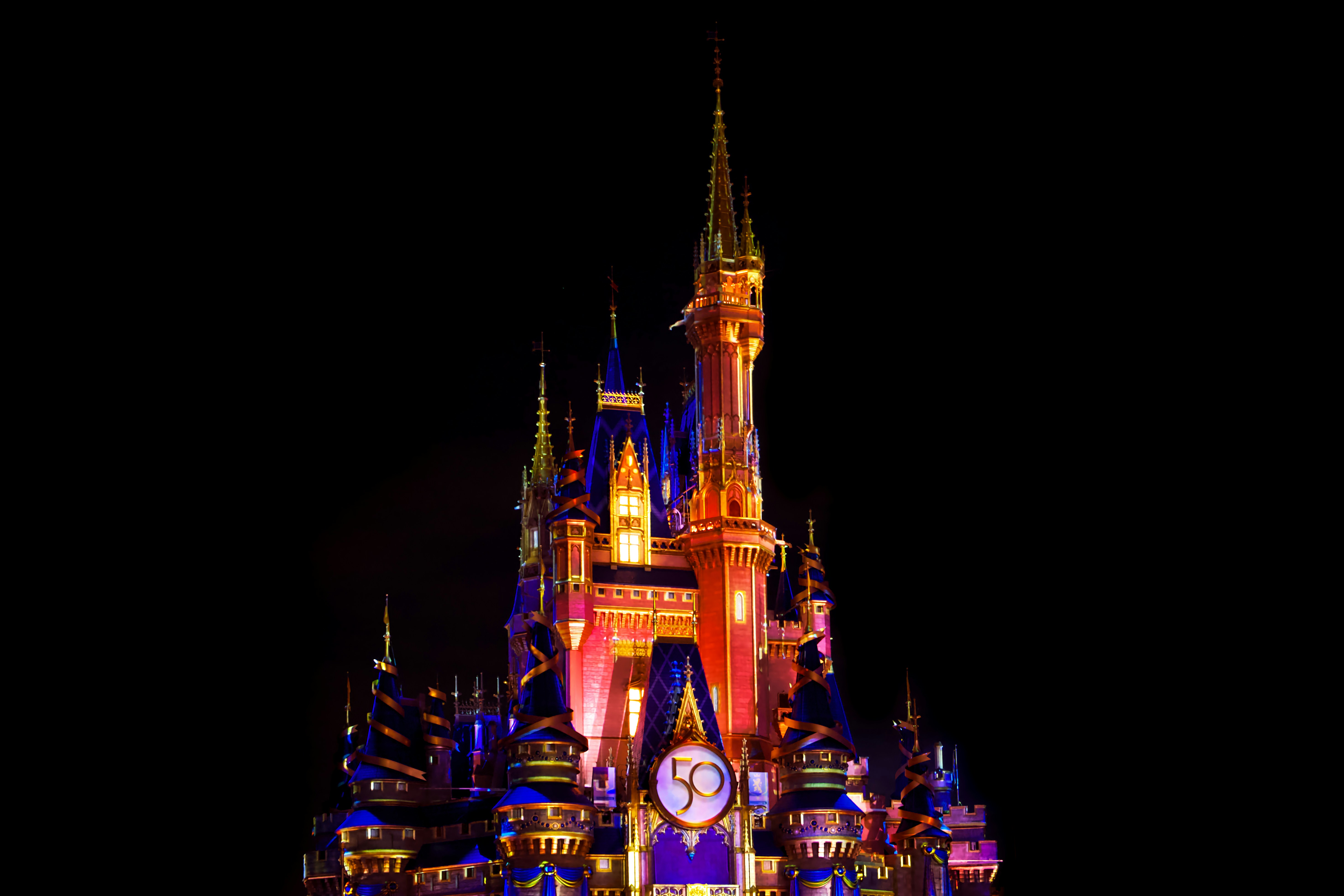 a castle lit up at night with a clock, Cinderella Castle dressed up for the Walt Disney World 50th Anniversary Celebration, Magic Kingdom