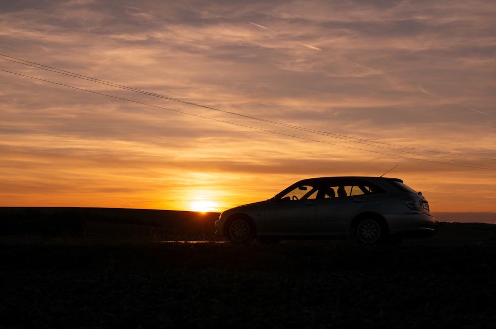 a car parked in a field at sunset