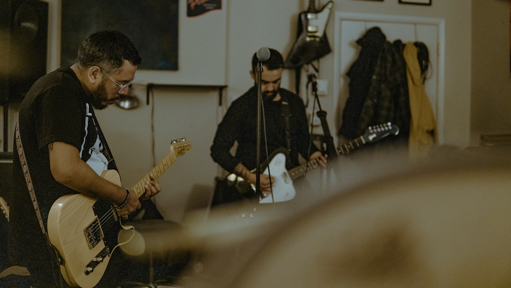 two men playing guitars in a room