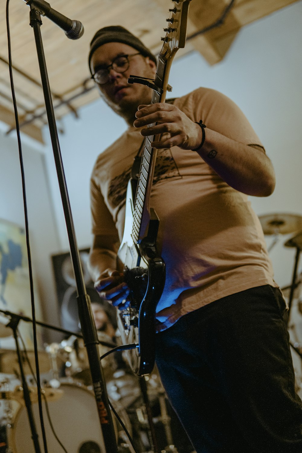 um homem tocando uma guitarra na frente de um microfone